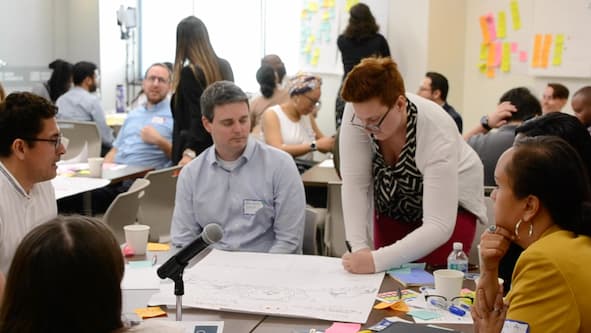 workshop participants huddling around a large sticky pad