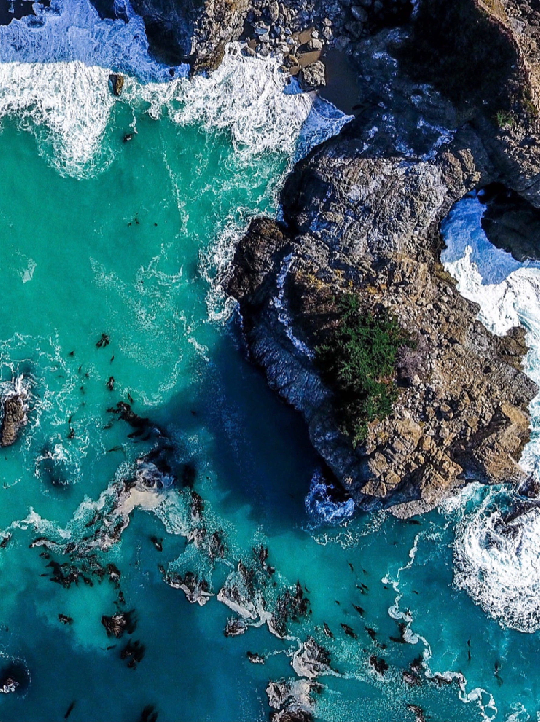 Blue ocean waves crashing into a rocky coastline.